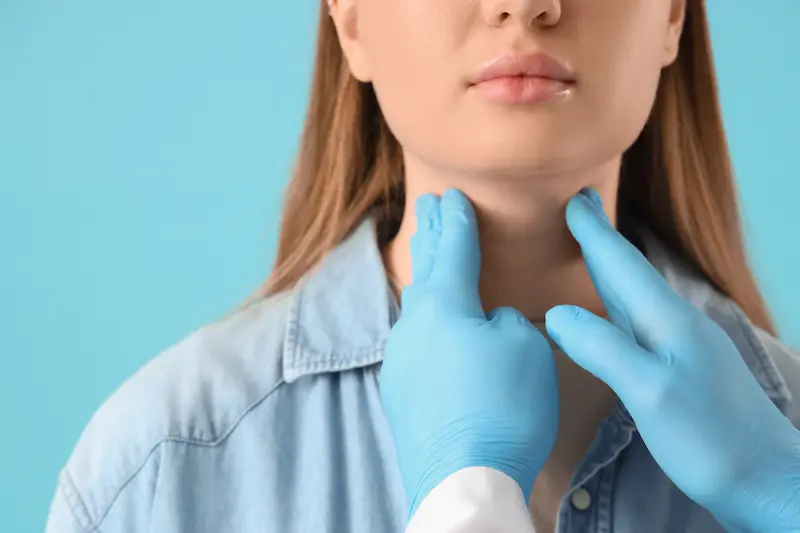 Осмотр при заболевании щитовидной железы: врач пальпирует шею пациентки.