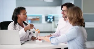 Замена плечевого сустава в Турции: врач консультирует пару, используя анатомическую модель плеча.